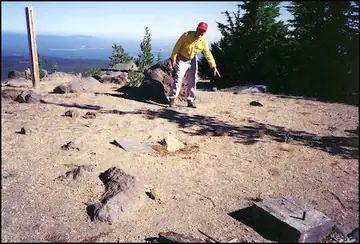 The flagstone landing that Richard Spray points to in the photo is all but invisible unless you are directly above it. The marker post is on the left. Two of the foundation blocks are in the foreground.
